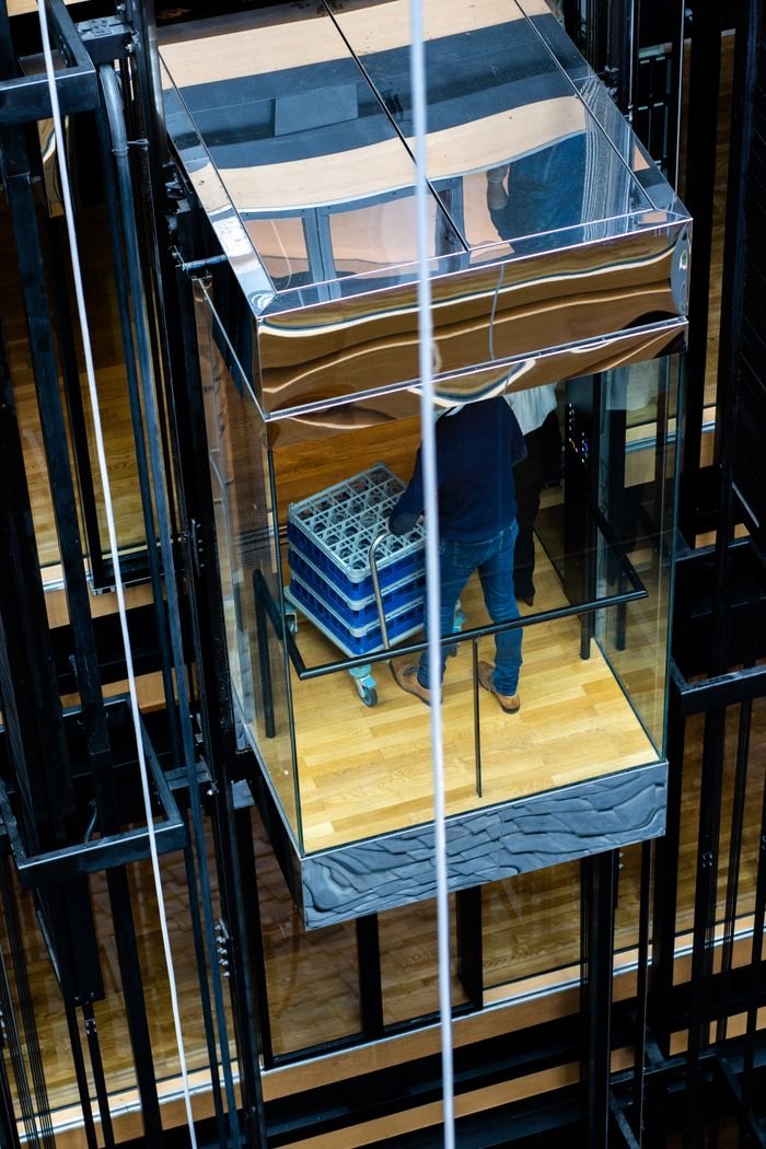 Person in a glass elevator with crates at an industrial setting. Captured in Strasbourg.