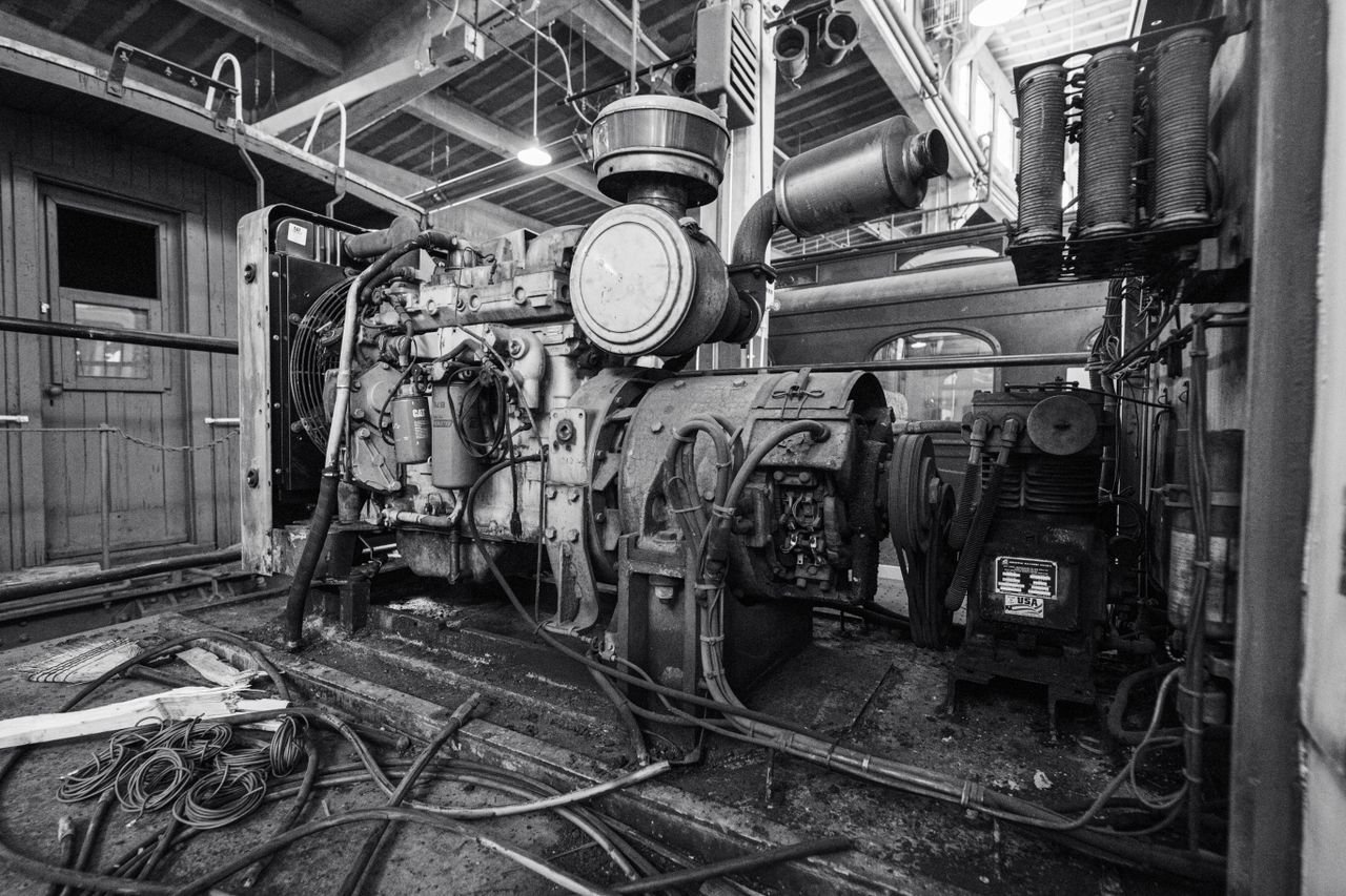 Black and white image of a vintage industrial engine inside a building.